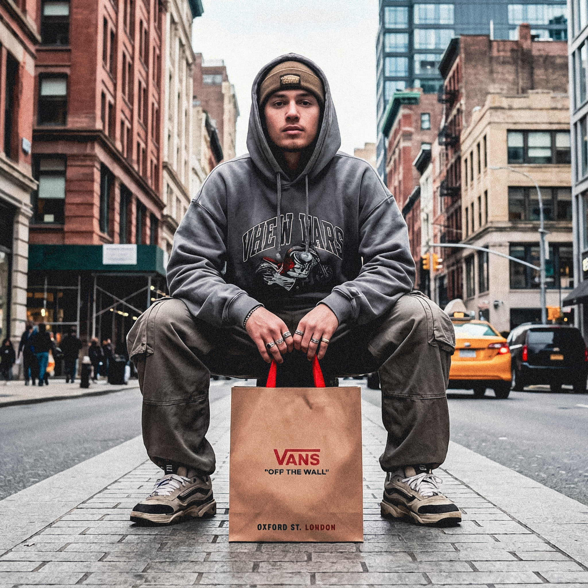 Firefly_Gemini Flash_Create a full-colour urban street-style fashion photo. A young man sits in a low, con 893857-3